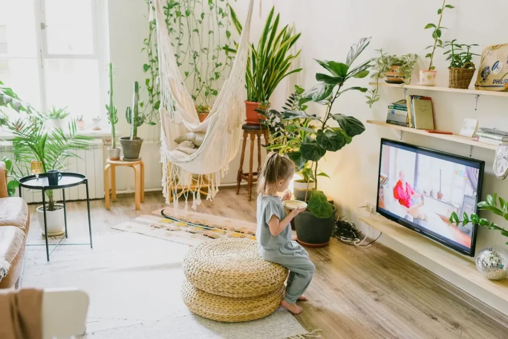 Criança Assistindo Desenho Animado em Sala Aconchegante e Com Muitas Plantas