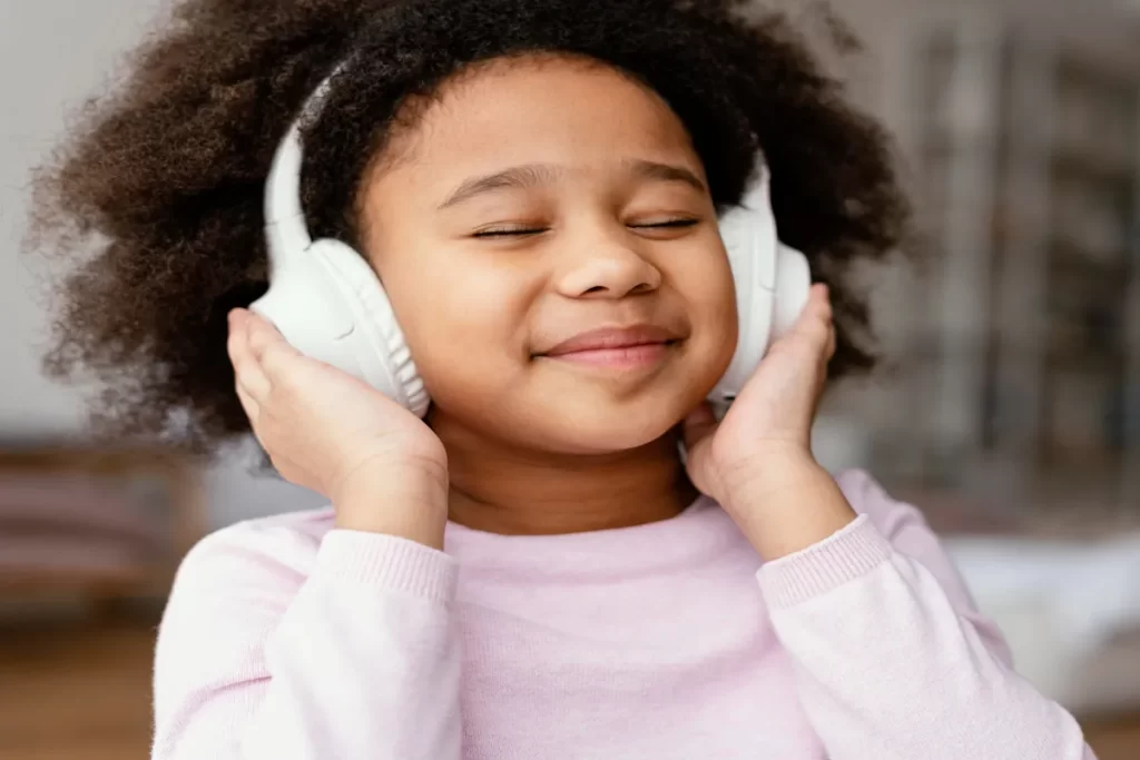 Criança sorridente ouvindo músicas infantis com fones de ouvido brancos
