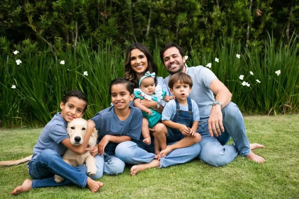 O empresário e coach Pablo Marçal, sua esposa e quatro filhos, junto a um cachorro, sentados na grama em um retrato de família.