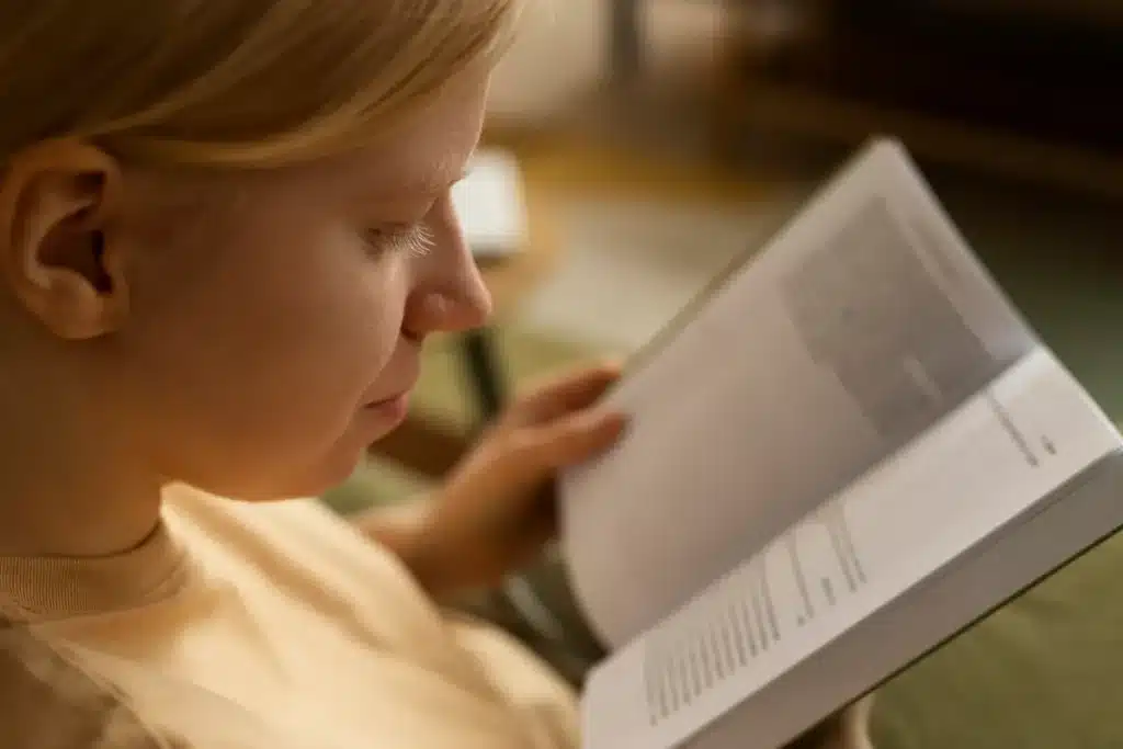 Menina lendo um livro em ambiente aconchegante durante momento de leitura e aprendizado infantil