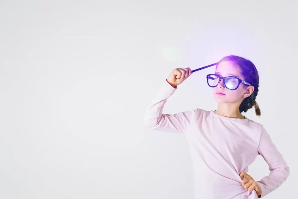 Menina com óculos grandes segurando um lápis na testa, simbolizando criatividade e pensamento inovador, em fundo branco minimalista.