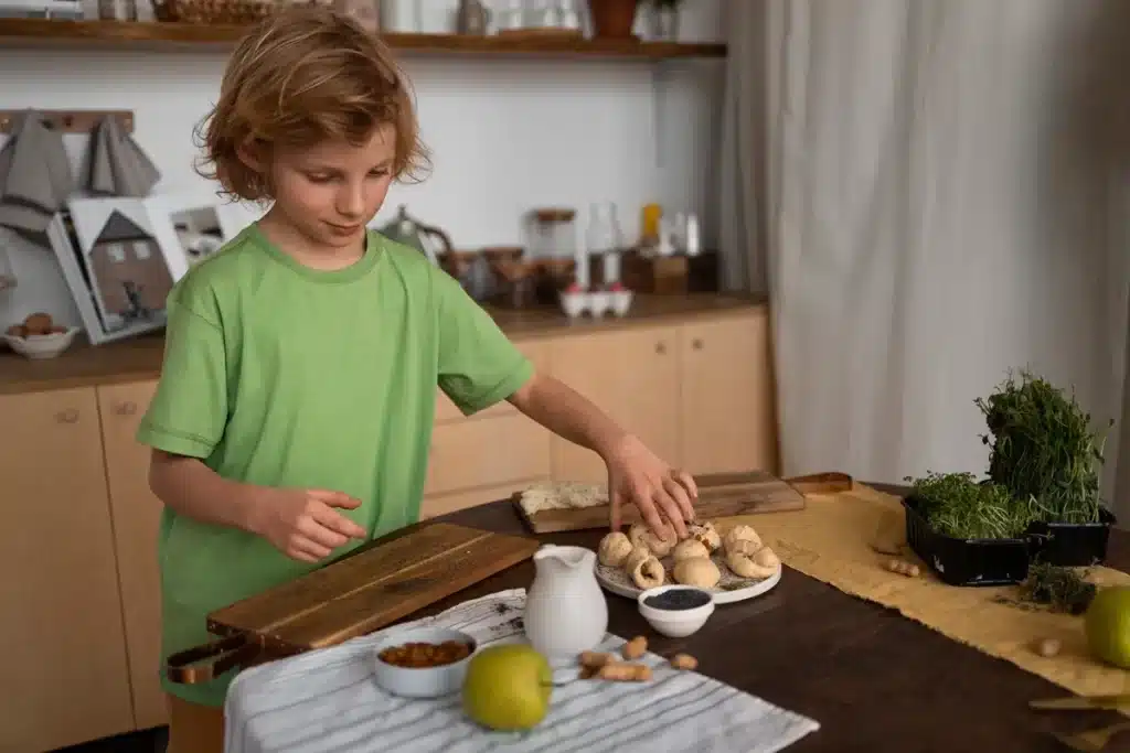 Criança em camiseta verde organizando ingredientes frescos, como ervas e especiarias, em uma cozinha.