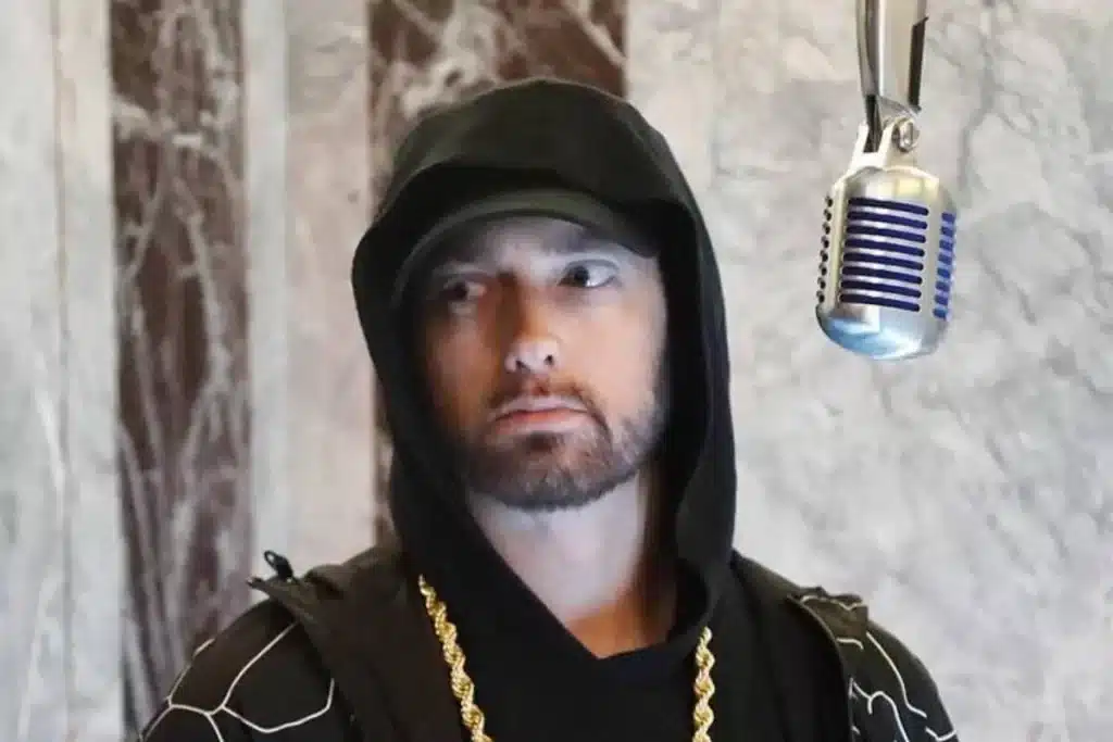 Retrato do rapper Eminem usando um moletom com capuz e boné em um estúdio de gravação, representando o artista em um conteúdo sobre sua família.