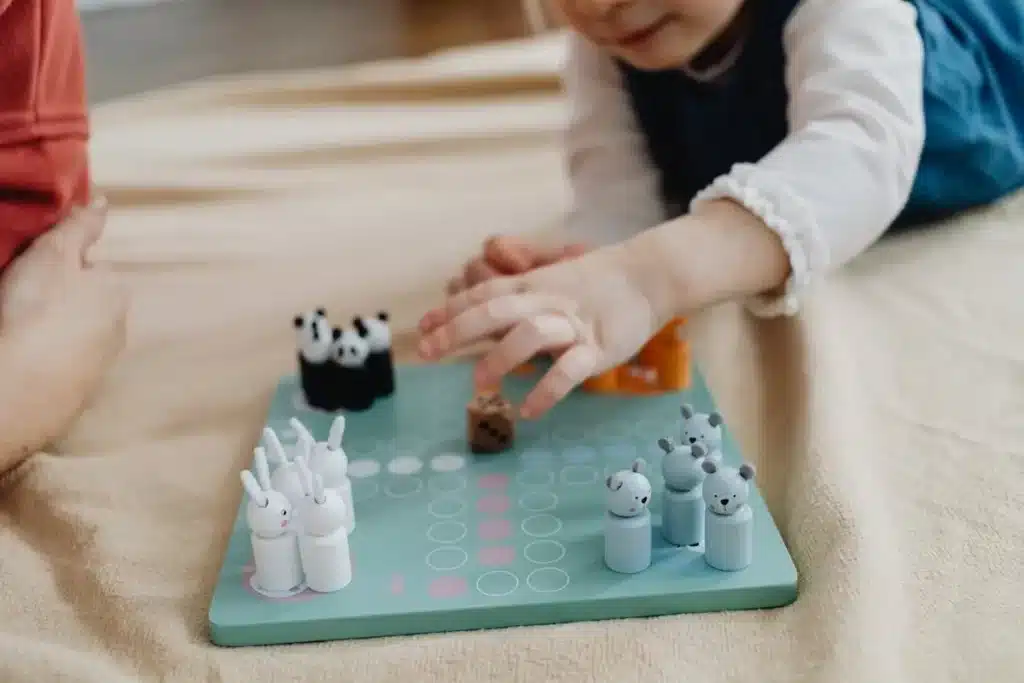 Criança pequena brincando com um jogo de tabuleiro de animais, ideal como brinquedo educativo para crianças de 1 ano.