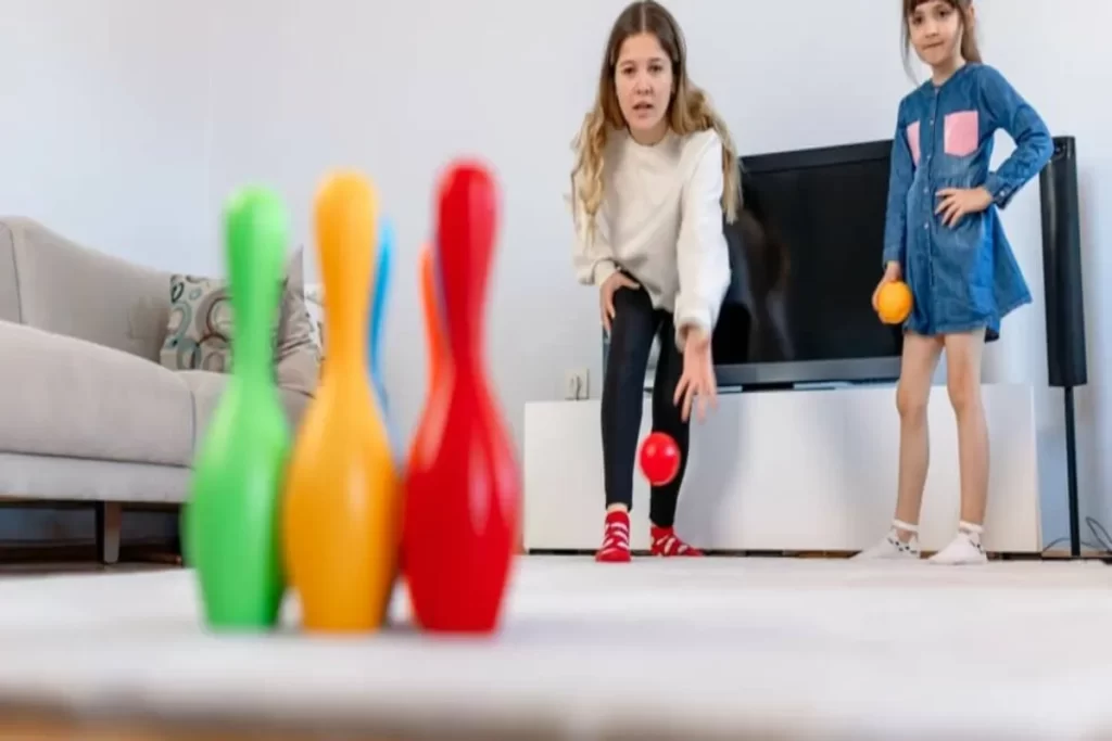Duas meninas brincando com boliche infantil colorido dentro de casa, exemplo de brinquedos para uma criança de 10 anos.