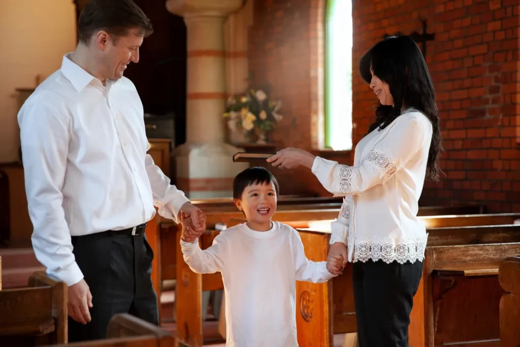 Família em uma igreja celebrando a Primeira Comunhão, com um menino alegre de mãos dadas com os pais.