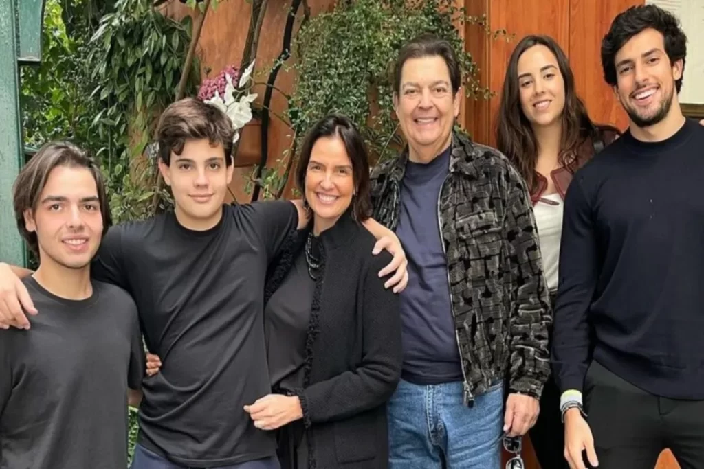 Faustão, sua esposa Luciana Cardoso e os filhos João Guilherme, Rodrigo e Lara em uma foto de família, todos sorrindo.