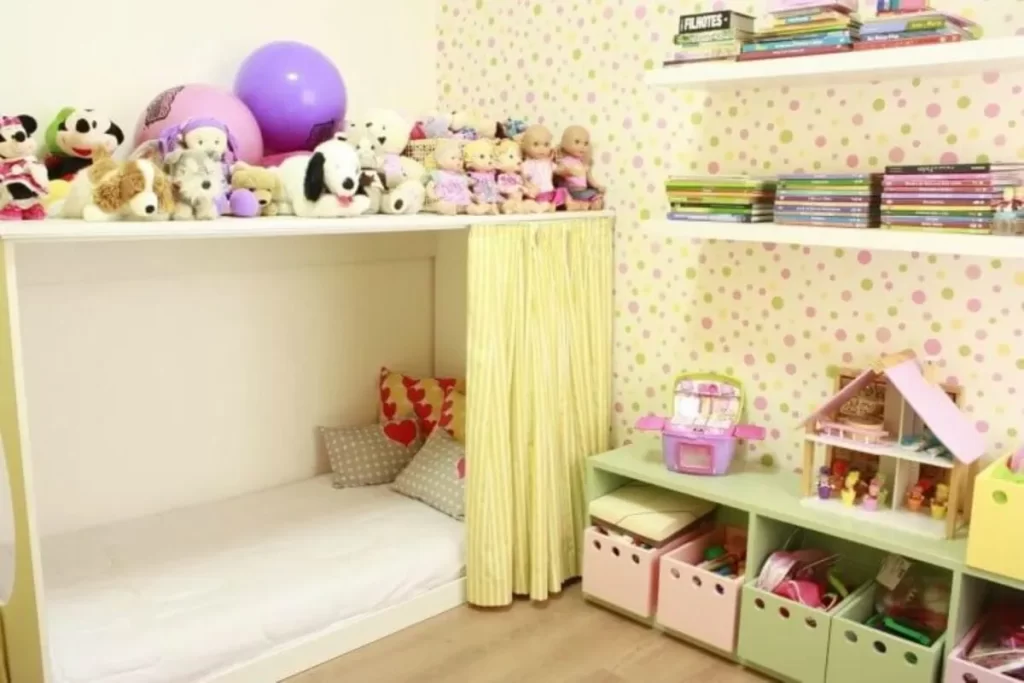 Quarto infantil organizado com prateleiras de livros, caixas coloridas para brinquedos e cama baixa com almofadas.