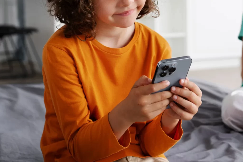 Criança segurando um celular, representando a importância do controle parental no uso de tecnologia