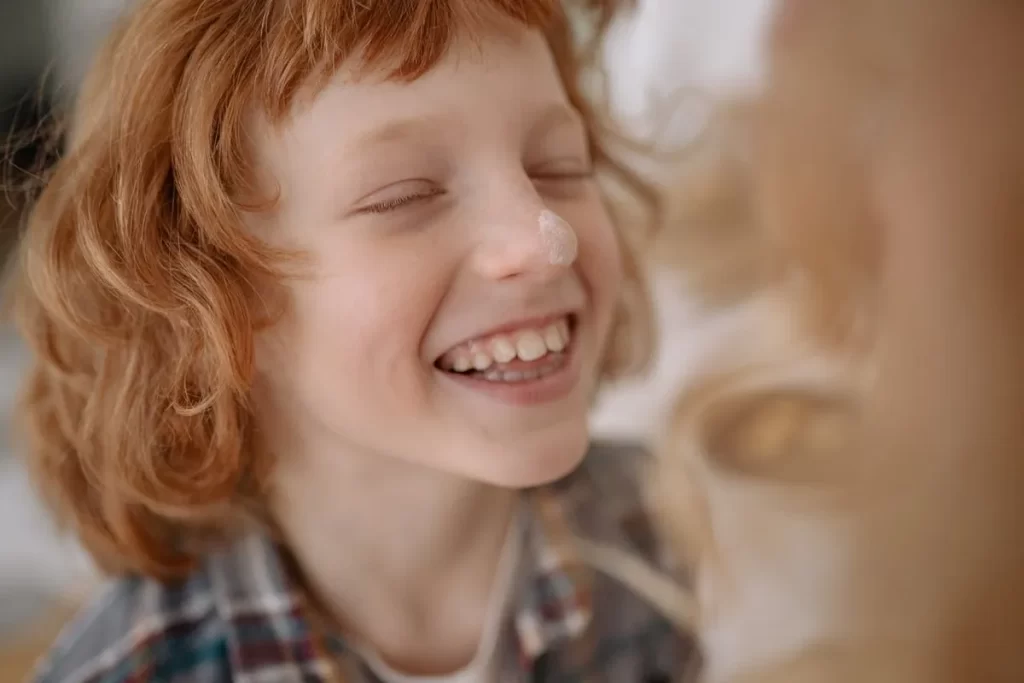 Criança sorrindo com os dentes à mostra, representando saúde bucal e prevenção da gengivite.