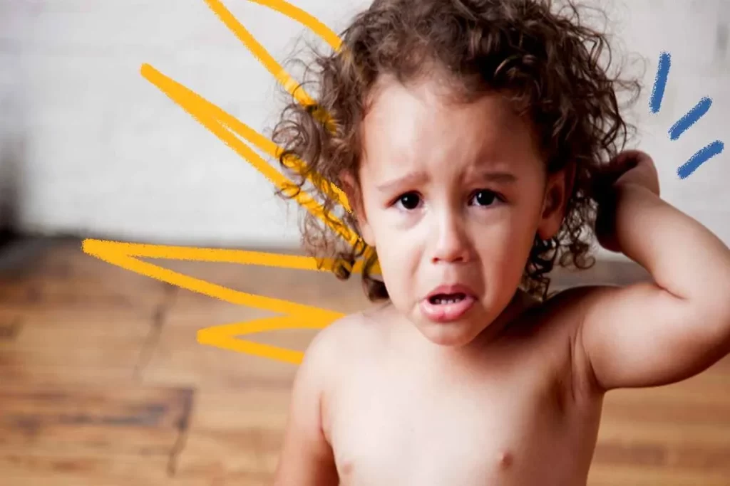 Criança pequena com cabelos cacheados chorando, ilustrando a dificuldade na regulação emocional.