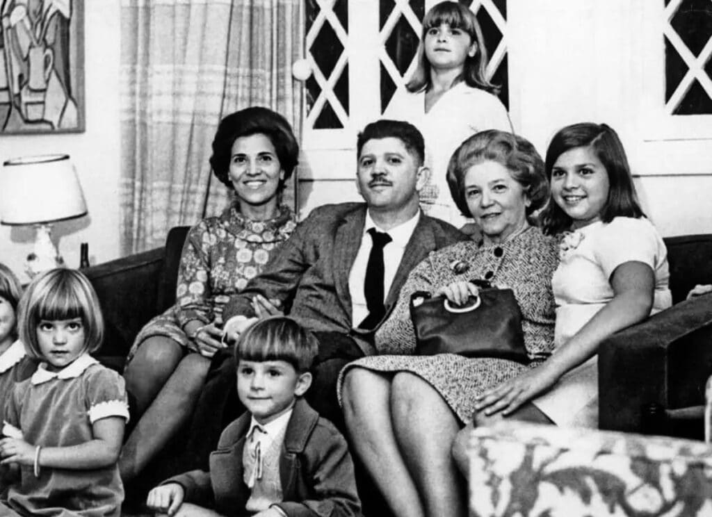Foto antiga em preto e branco de família reunida na sala de estar nos anos 1960