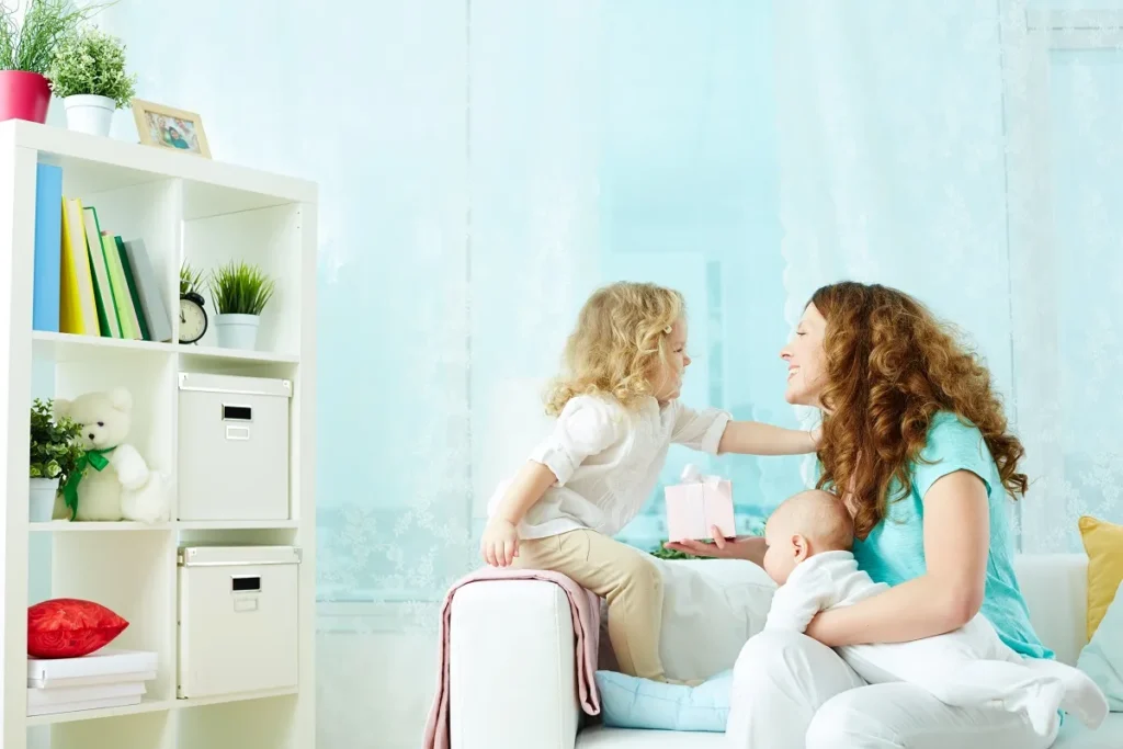 Mãe segurando a mão de bebê recém-nascido no colo durante amamentação em plano detalhado.