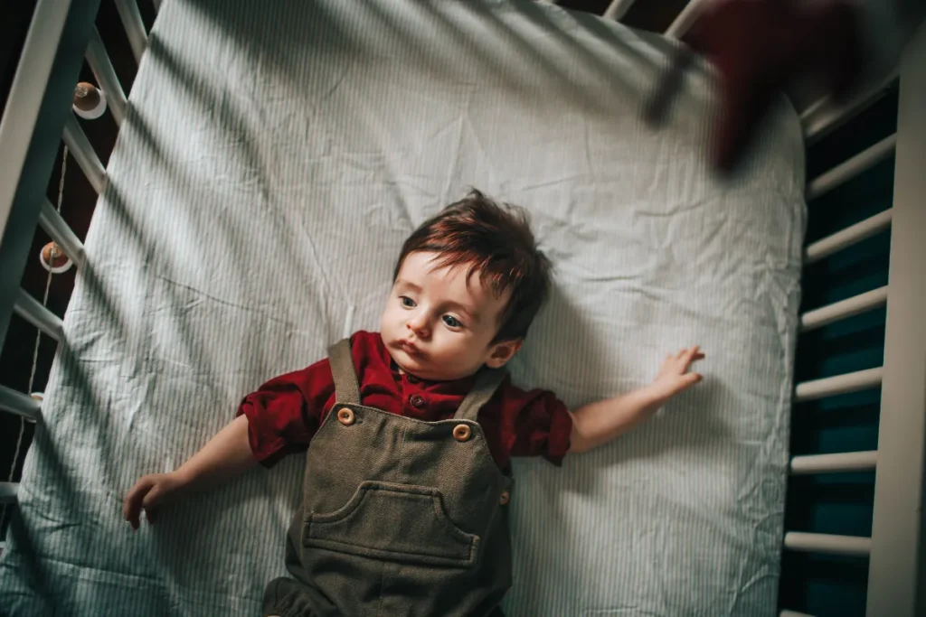 Bebê deitado em colchão firme dentro do berço durante momento de descanso seguro e confortável.