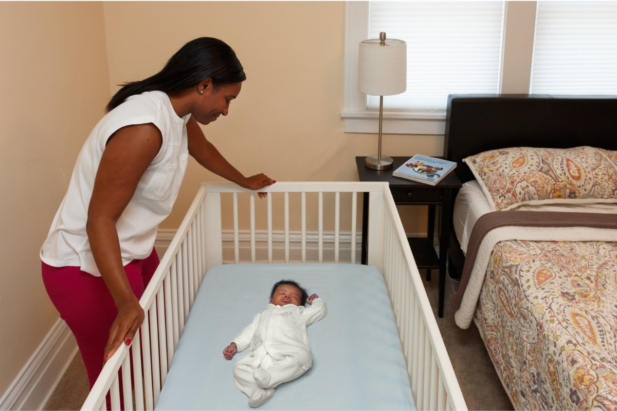 Berço infantil em área de sono separada e próximo à cama dos adultos