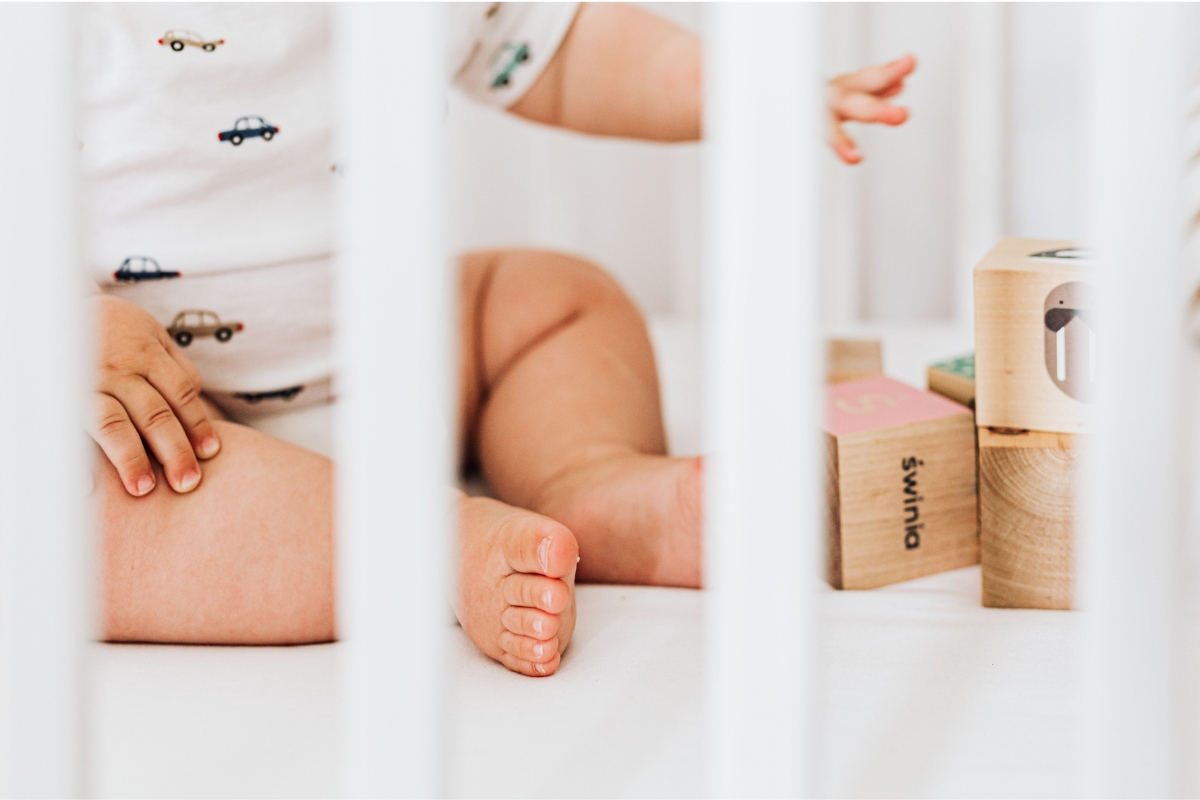 Bebê sentado em berço brincando com blocos de madeira