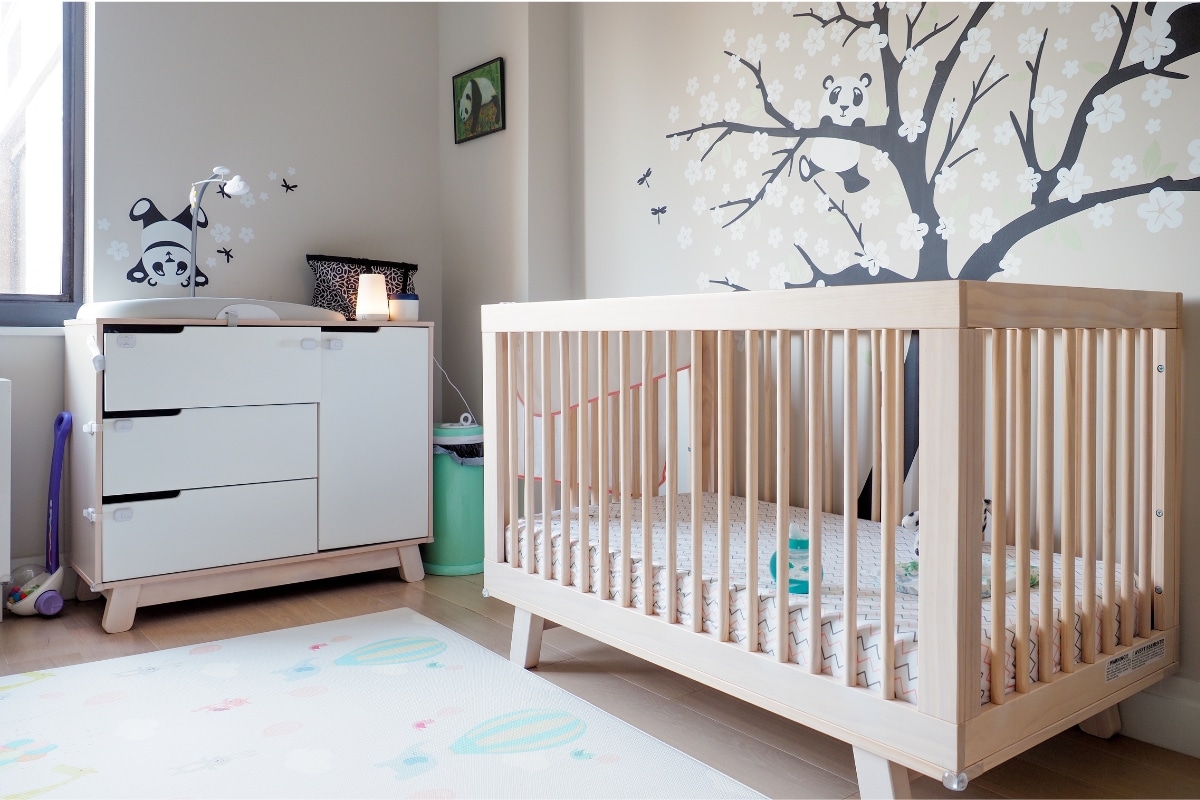 Quarto de bebê com berço posicionado junto à parede e móveis ao redor.