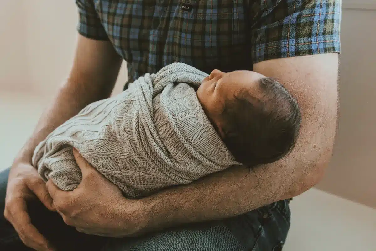 Cuidador segurando um bebê adormecido nos braços