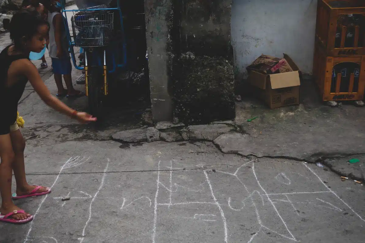 Criança brincando de piko no chão, uma variante da amarelinha