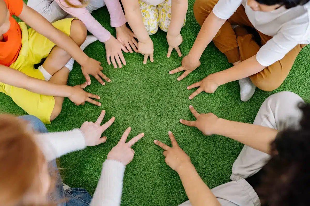 Crianças sentadas em círculo participando de uma brincadeira coletiva ao ar livre.
