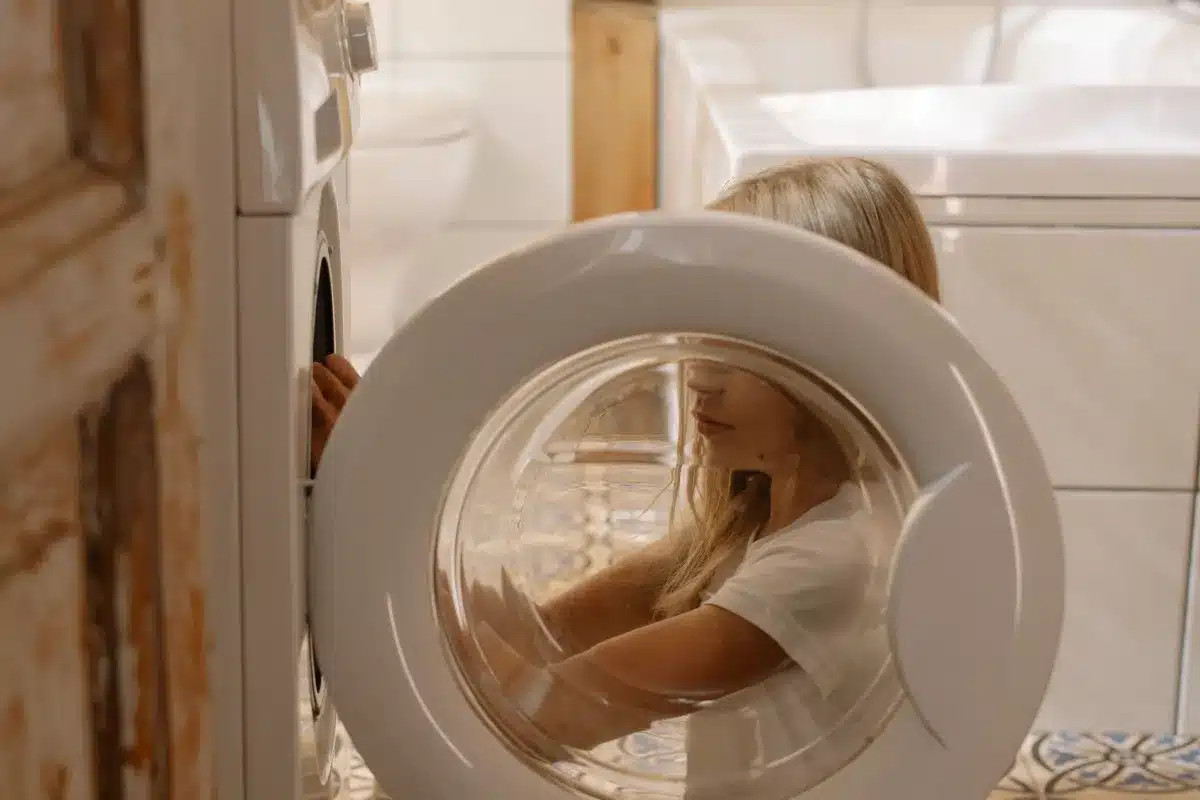 Criança participando da organização de roupas perto de uma máquina de lavar