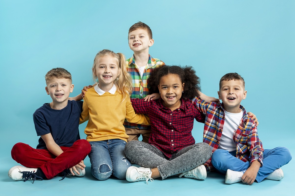 três meninos e duas meninas sentados em um fundo azul