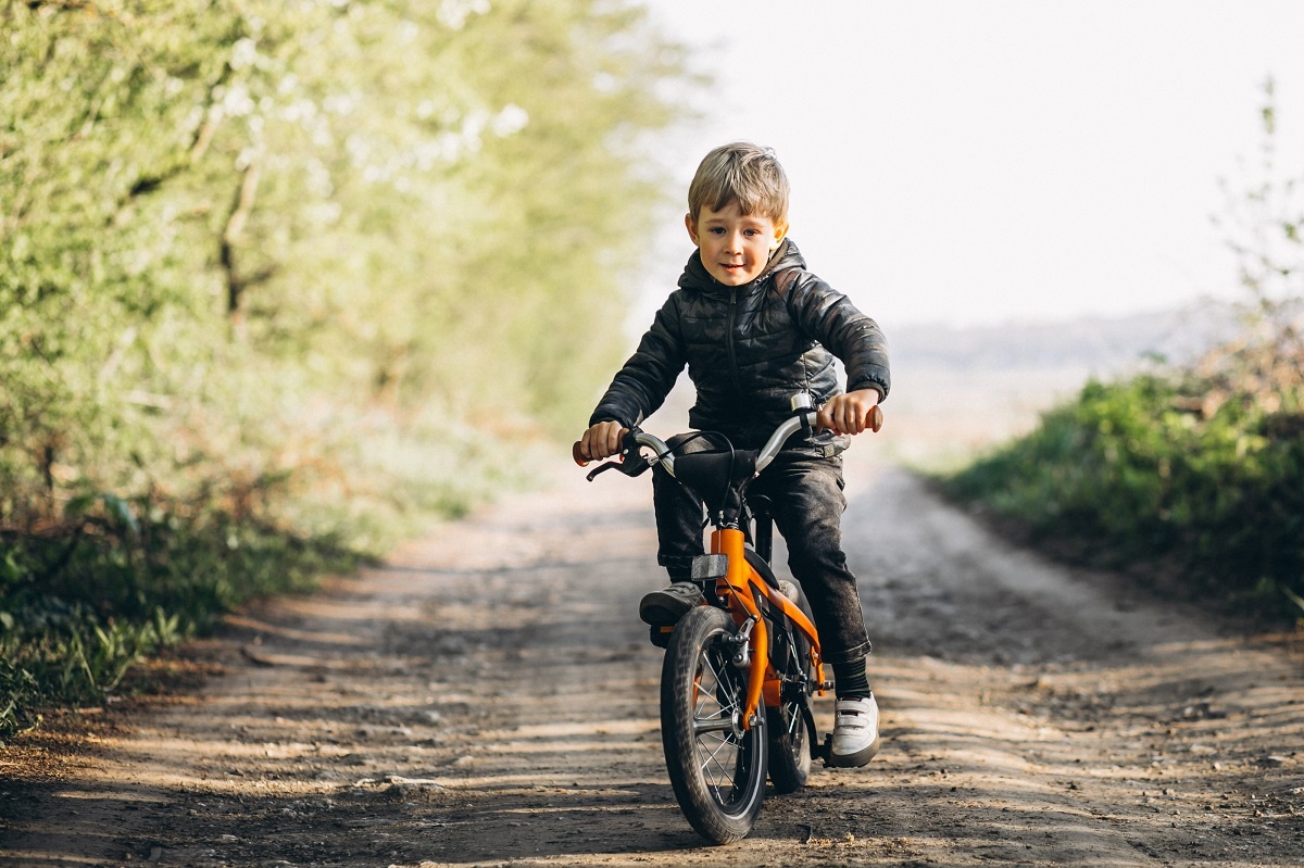 menino loiro andando de bicicleta