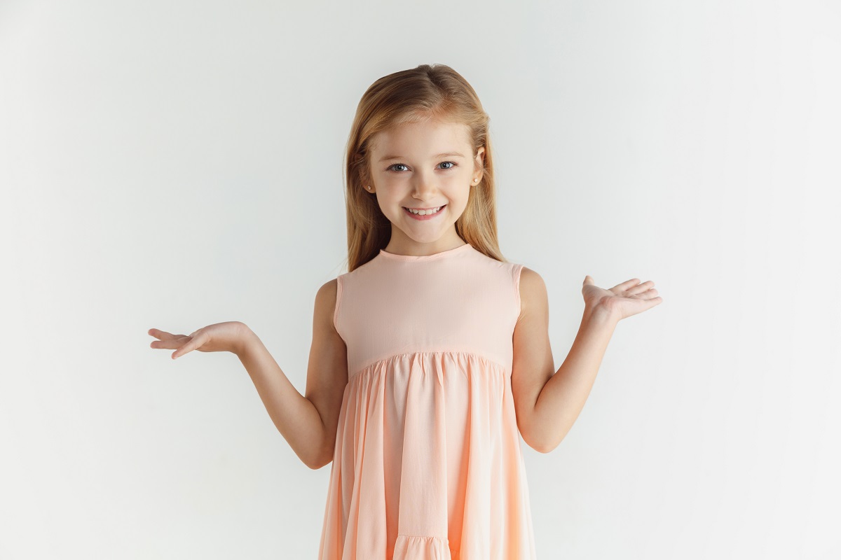 Menina sorridente elegante posando com vestido isolado na parede branca