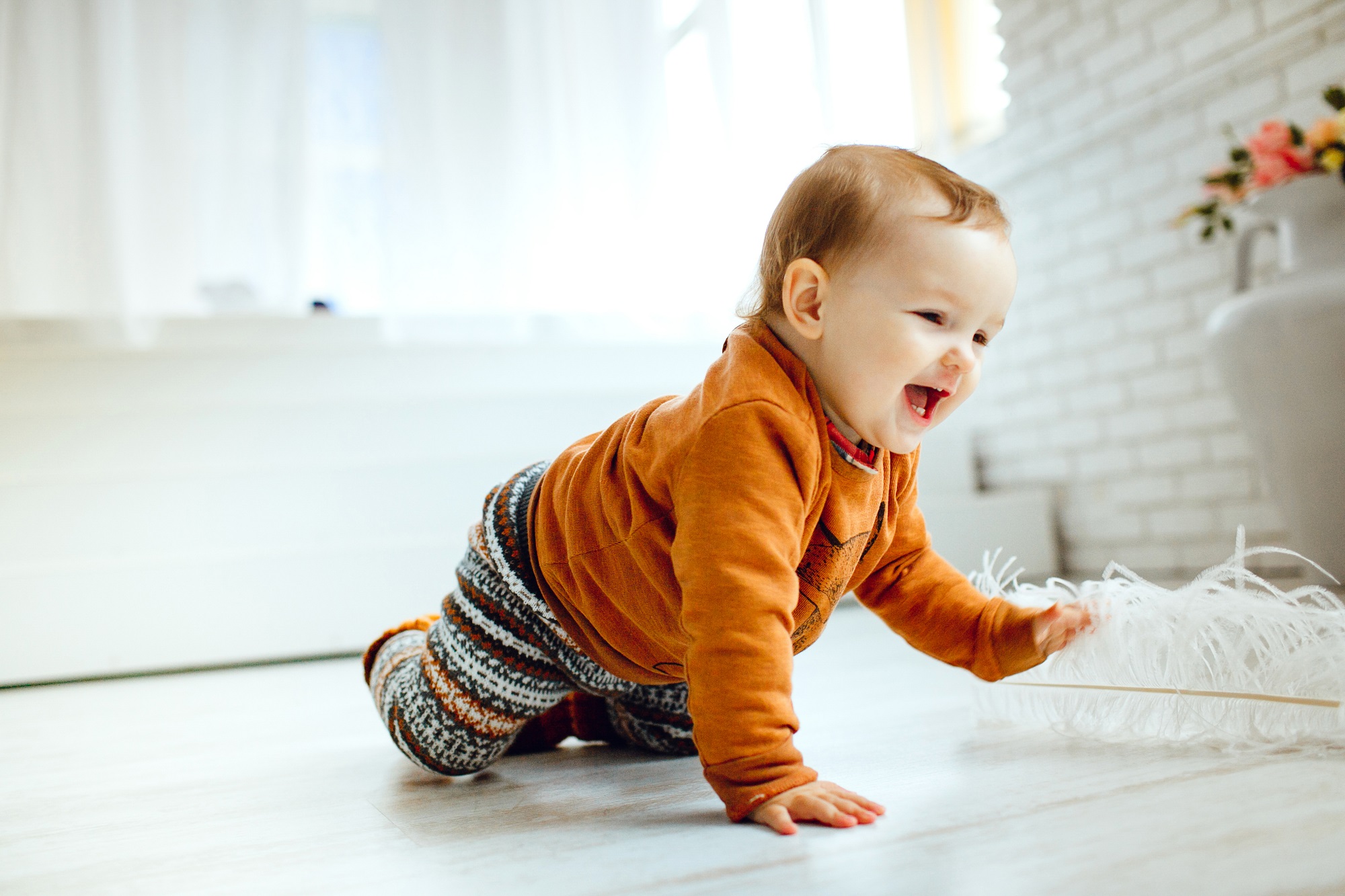 bebê engatinhando no chão e rindo muito alegre