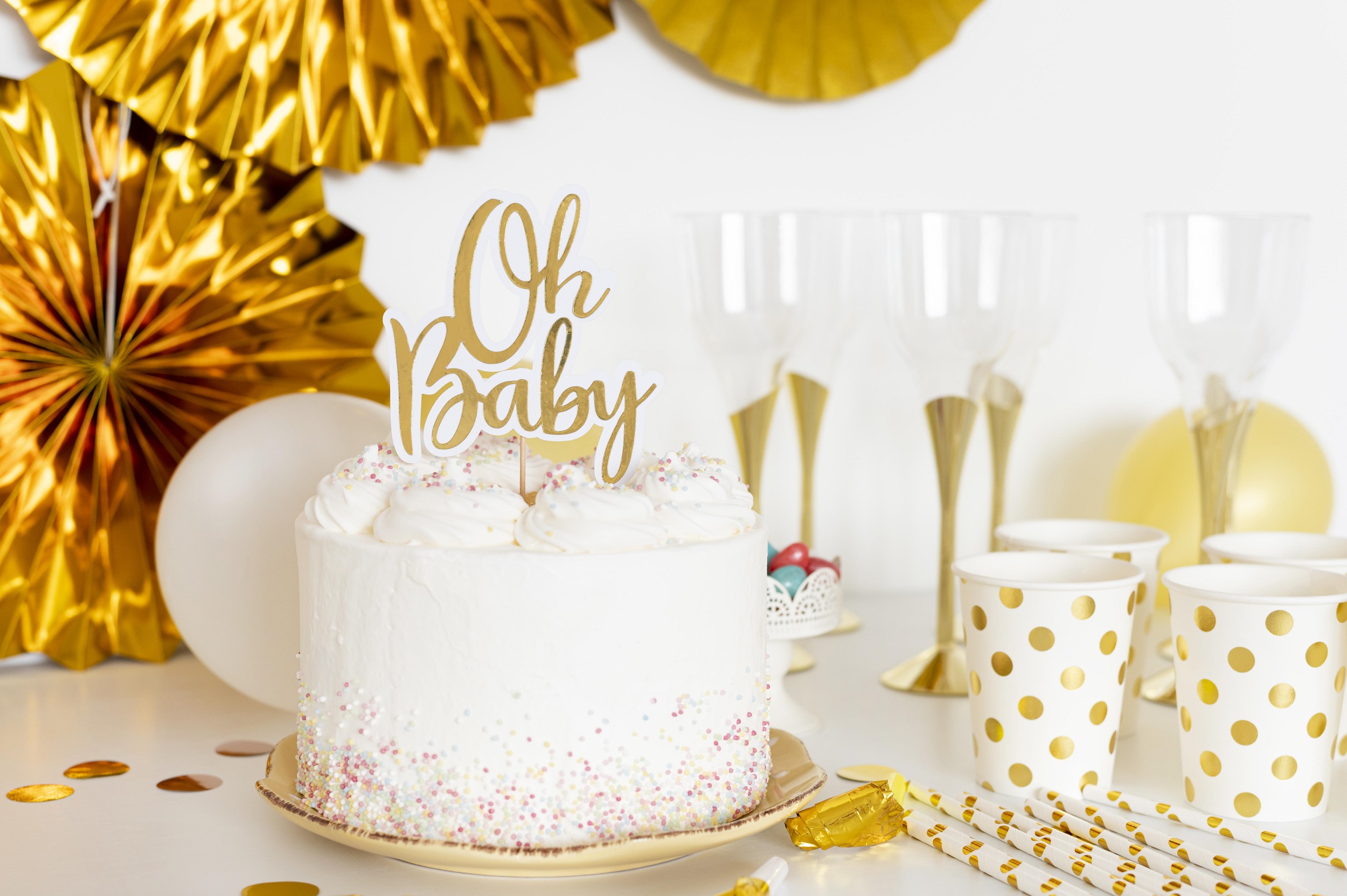 Vista frontal do conceito de bolo de chá de bebê e copos decorativos ao redor tudo em branco e dourado