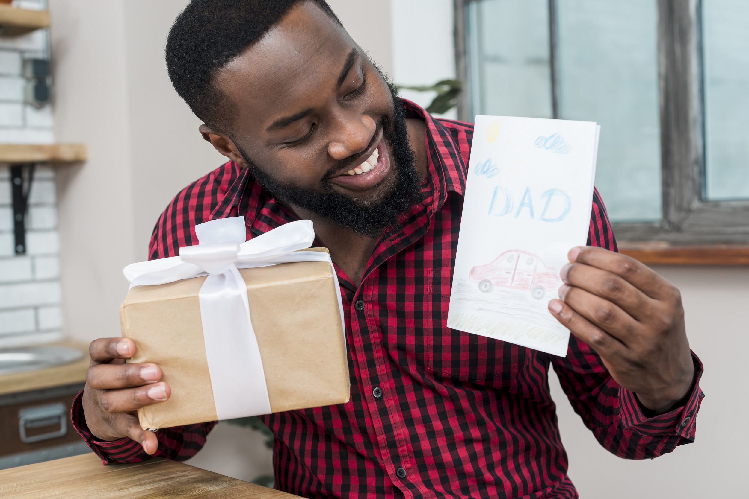 Homem negro feliz segurando o cartão de dia dos pais e presente