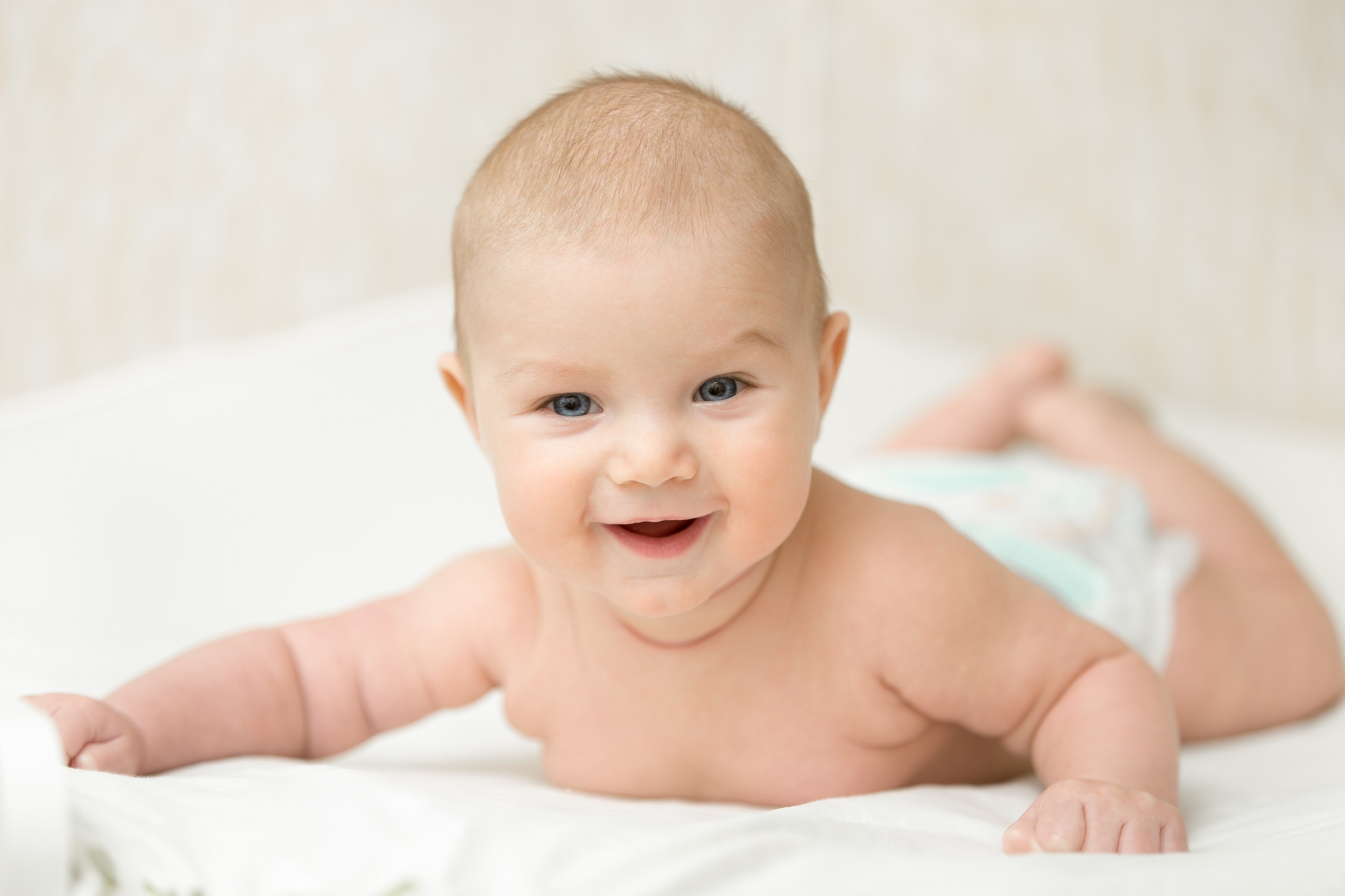 bebê feliz sorrindo deitado de bruços sem camisa