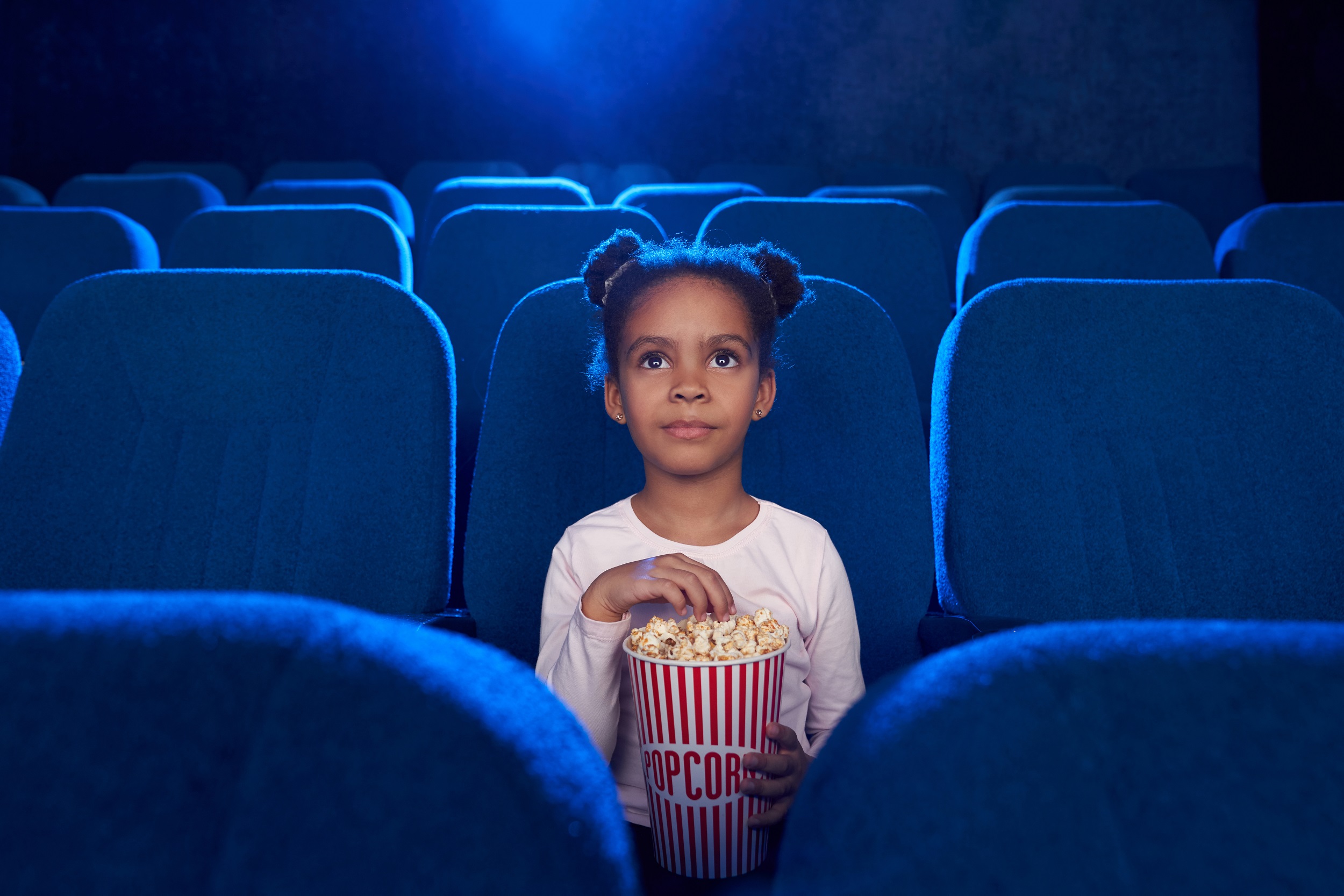 garota afro com um balde de pipoca sozinha em um cinema ou teatro