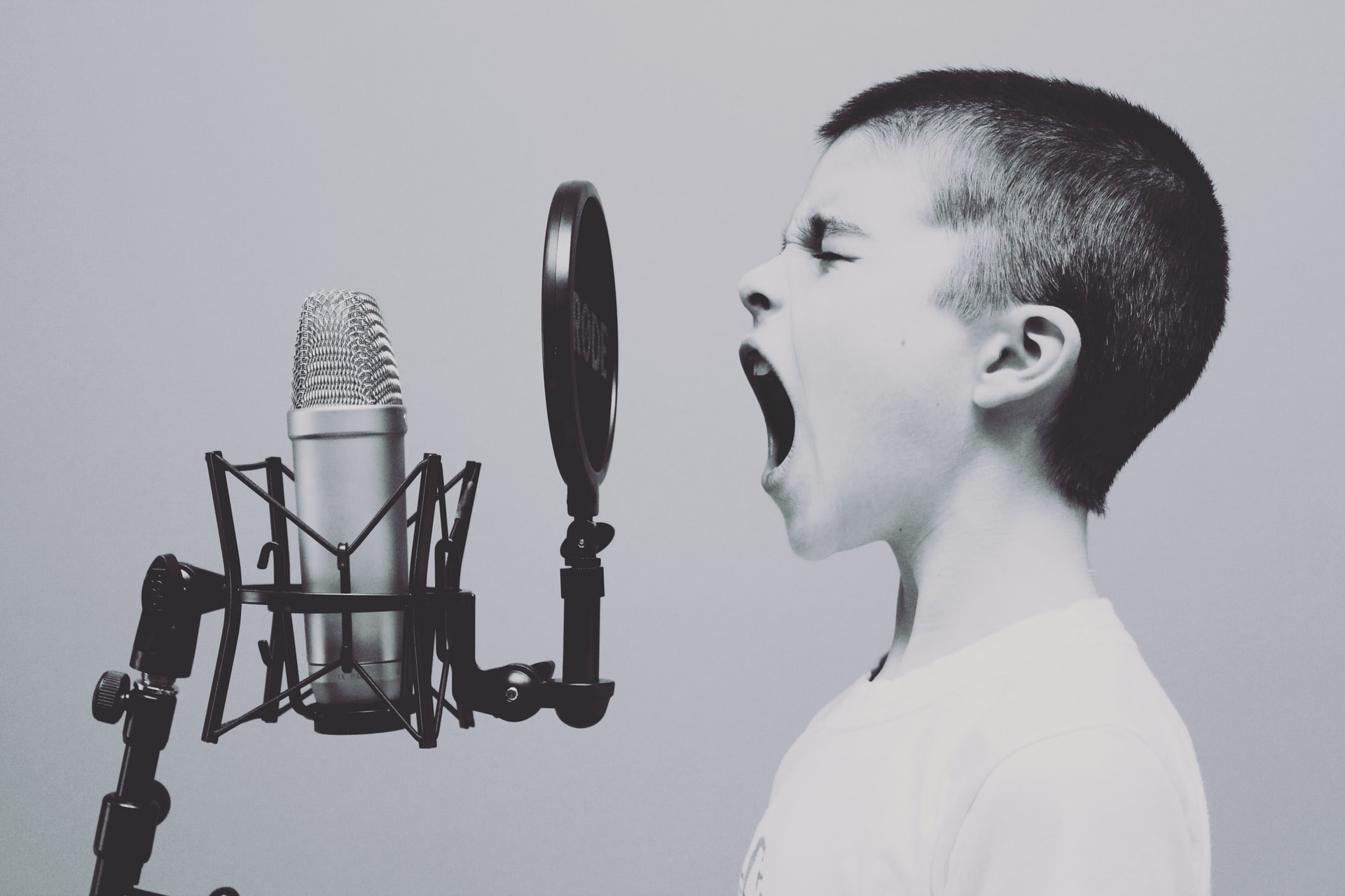 imagem em preto e branco de um menino gritando em um microfone