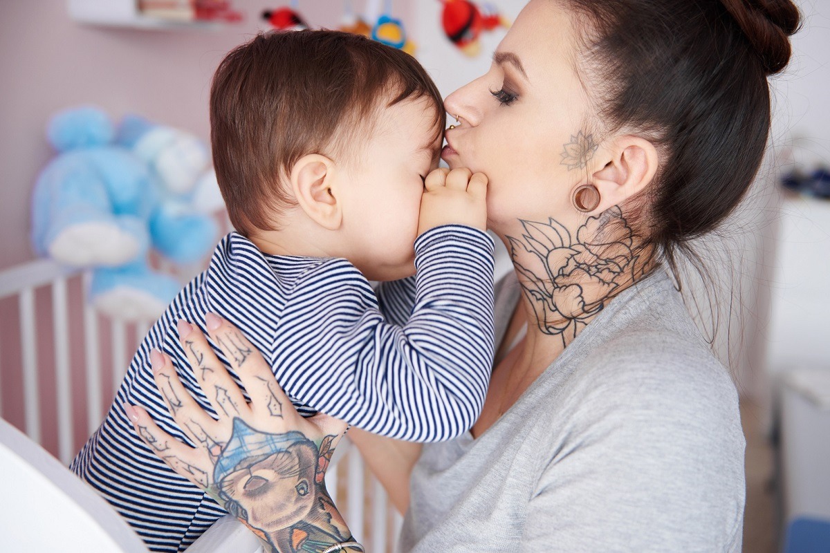 Mother kissing sleepy son on the forehead