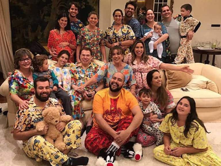 Silvio Santos com sua família reunida em uma noite descontraída, todos vestindo pijamas coloridos, simbolizando a união e a descontração familiar.