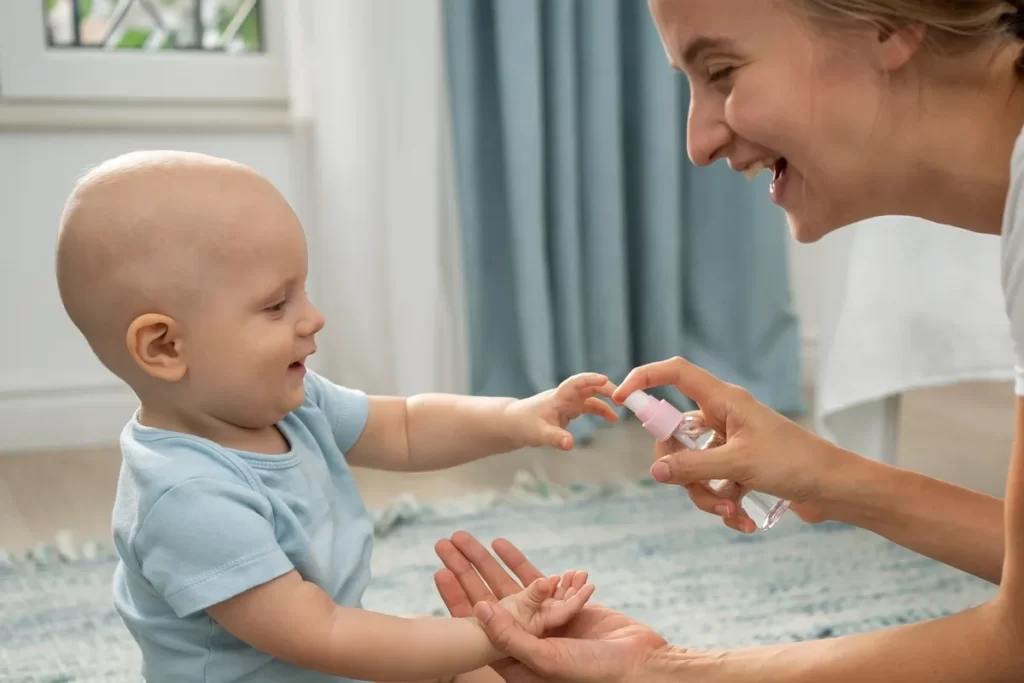 Mãe aplicando repelente em spray nas mãos de seu bebê sorridente em um ambiente interno