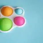 Brinquedo sensorial com bolhas coloridas em estrutura branca sobre fundo azul, usado para estímulo tátil infantil