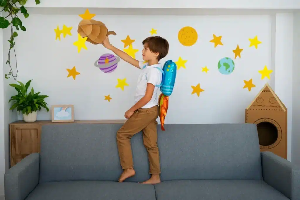Menino brincando de astronauta em casa, com mochila de foguete nas costas e decoração de planetas e estrelas na parede.