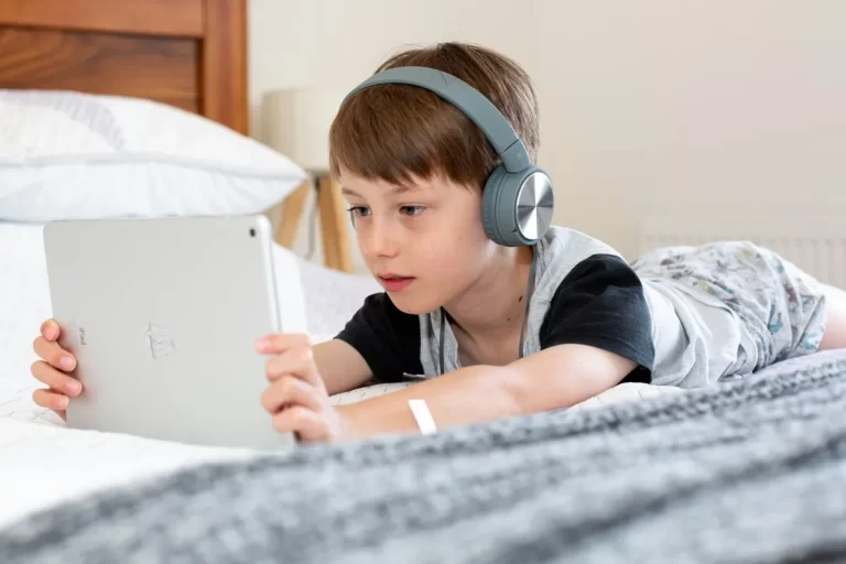 Menino usando fones de ouvido enquanto assiste a algo em um tablet.