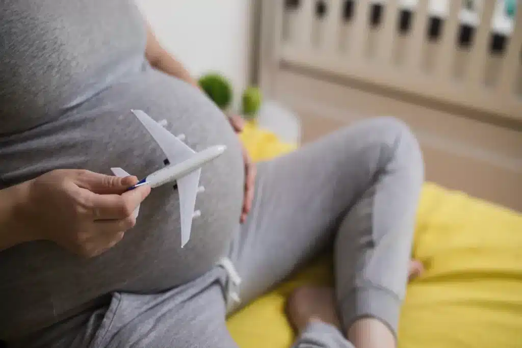 Mulher grávida segurando um avião de brinquedo sobre a barriga, simbolizando o planejamento e a dúvida "grávida pode viajar de avião".