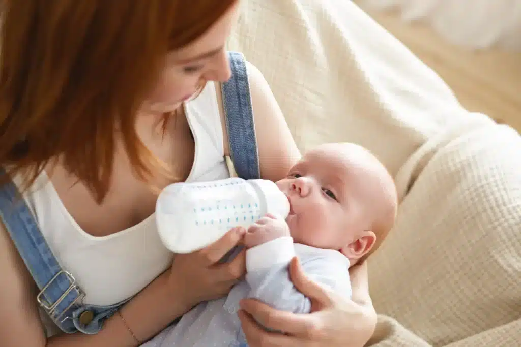 Mãe alimentando seu recém-nascido com mamadeira, focada no bebê. Conforto e nutrição infantil.