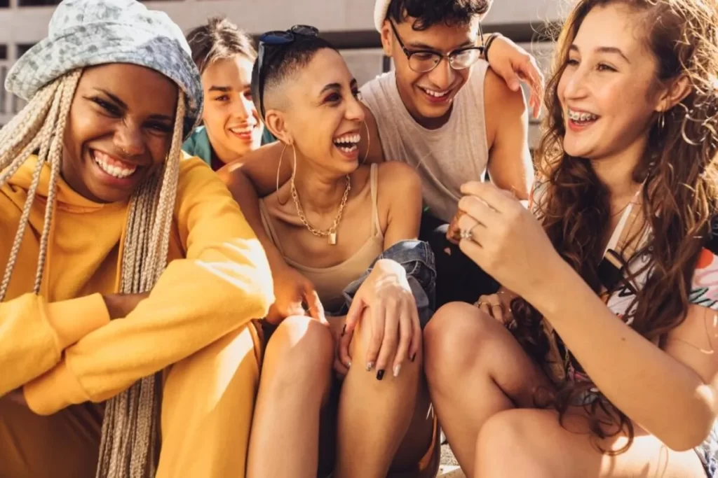 Grupo de jovens da Geração Z reunidos, sorrindo e conversando de forma descontraída, representando amizade, diversidade e conexão social.
