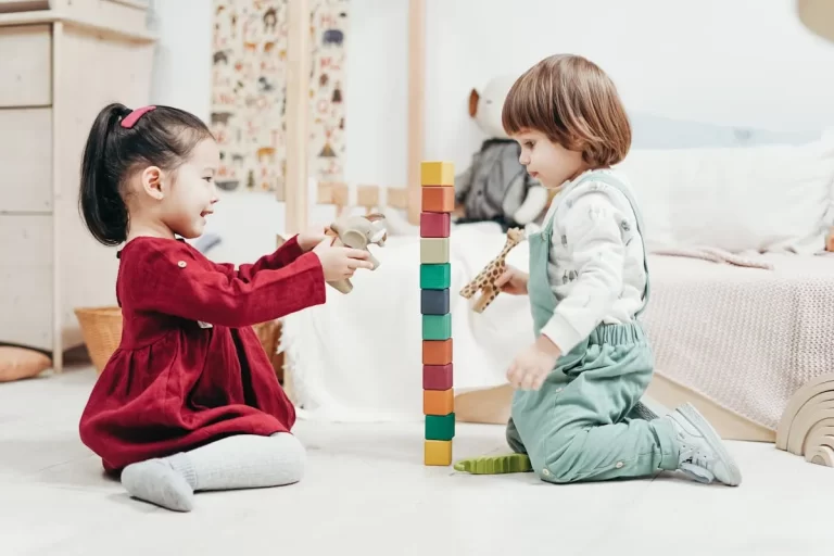 Duas crianças pequenas brincando com blocos coloridos, representando atividades de estimulação precoce