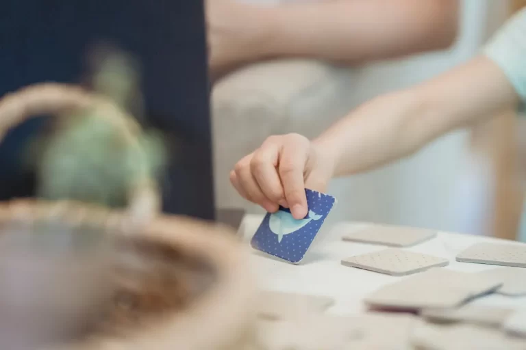 Criança segurando carta colorida durante uma brincadeira, representando o uso de jogos de memória infantil para estimular o aprendizado