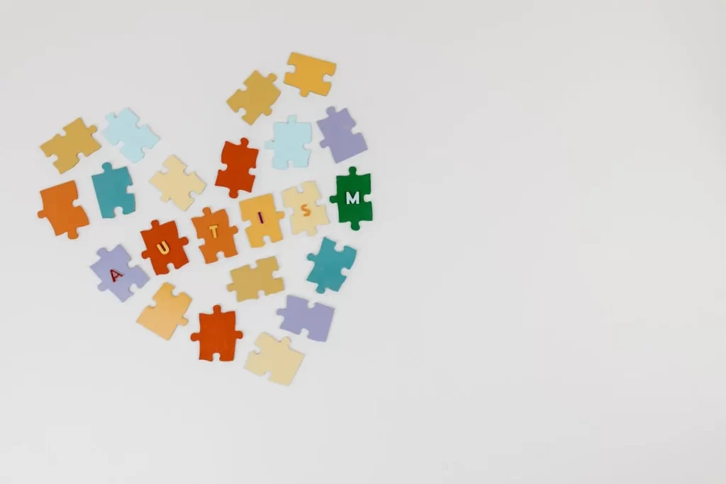 Peças coloridas de quebra-cabeça formando um coração com a palavra autismo, simbolizando a inclusão de crianças neurodivergentes