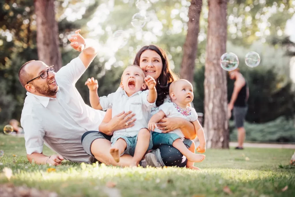 Família nuclear com pais e filhos brincando no parque, representando amor e união familiar