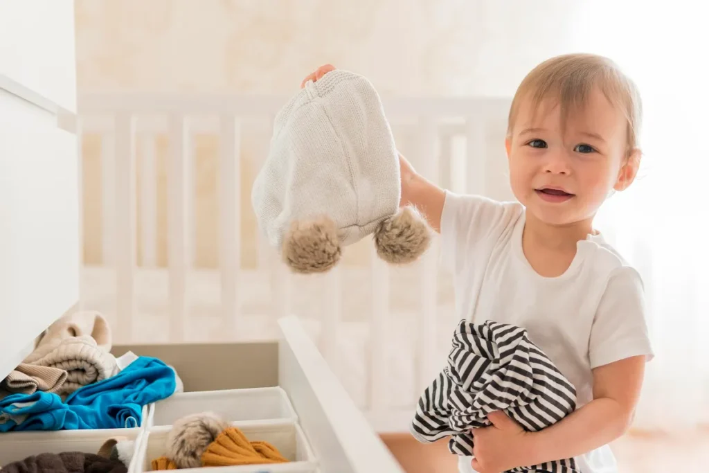 Guarda-roupa de bebê planejado em MDF branco com nichos abertos iluminados por LED, gavetas, roupas penduradas em cabides e ursos de pelúcia decorativos.