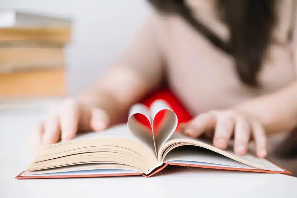 Livro aberto com páginas formando um coração enquanto criança lê em ambiente tranquilo