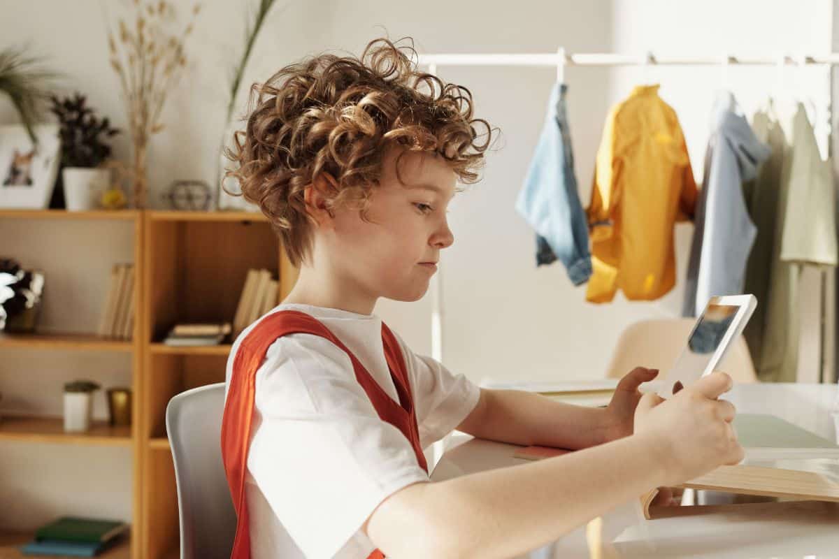 Criança usando um tablet em uma mesa de estudos